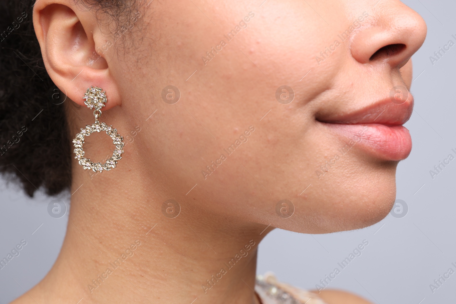 Photo of Young woman wearing elegant earring on light grey background, closeup