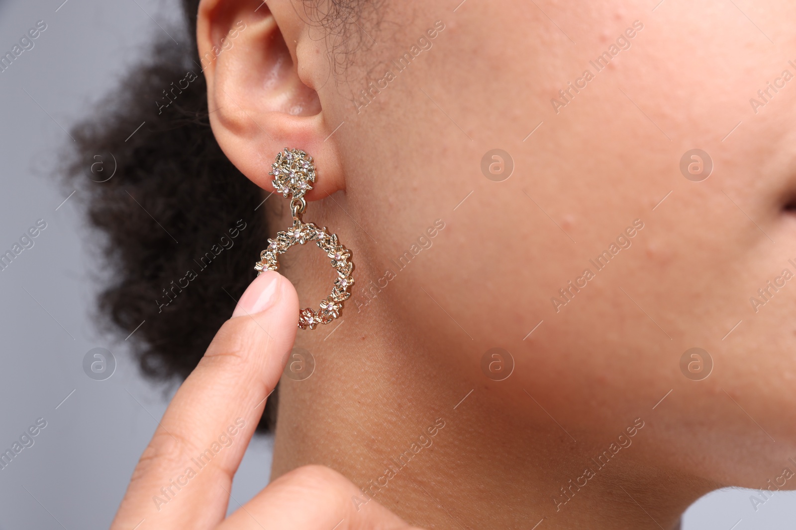 Photo of Young woman wearing elegant earring on light grey background, closeup