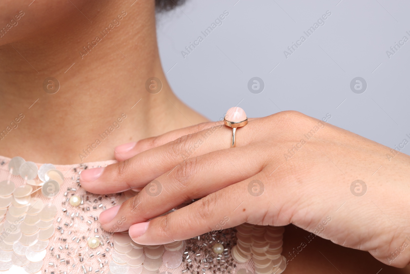 Photo of Young woman wearing elegant ring on light grey background, closeup