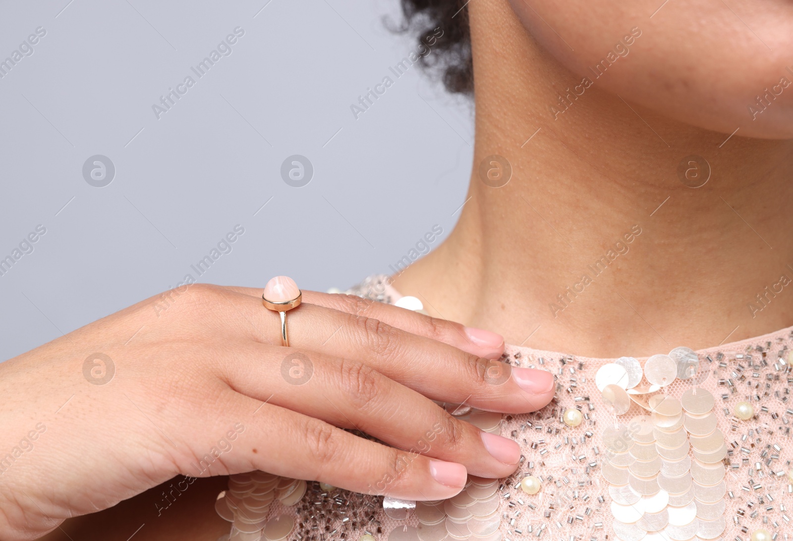 Photo of Young woman wearing elegant ring on light grey background, closeup
