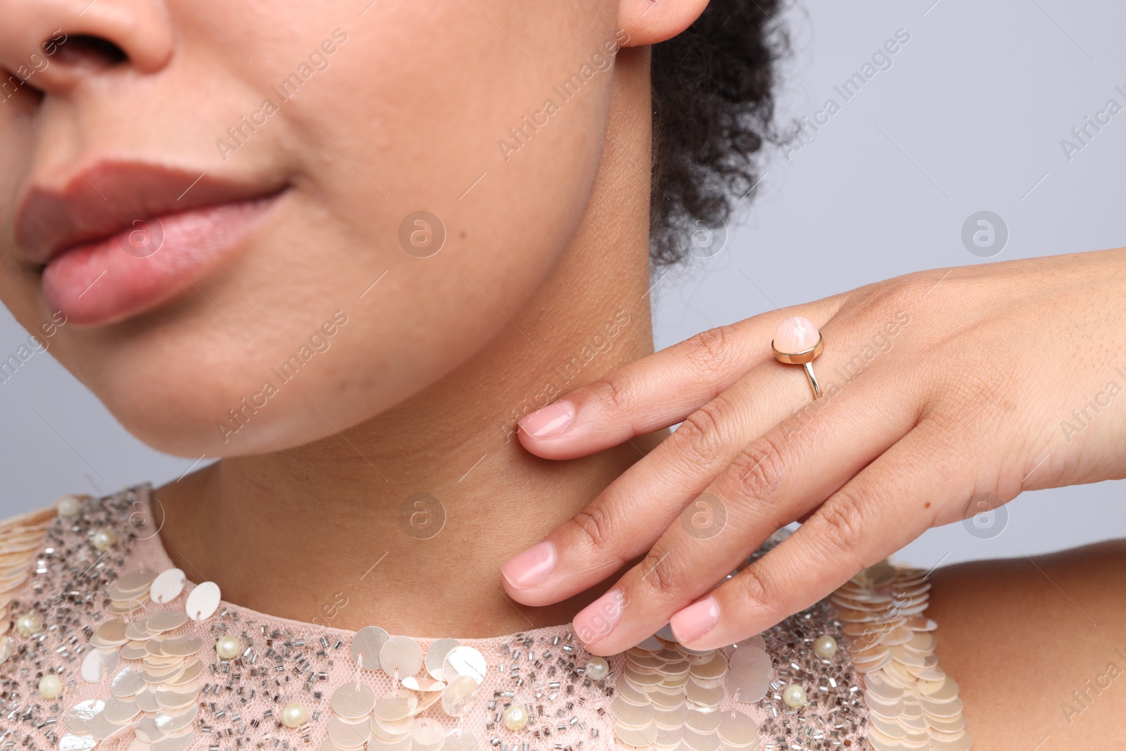Photo of Young woman wearing elegant ring on light grey background, closeup