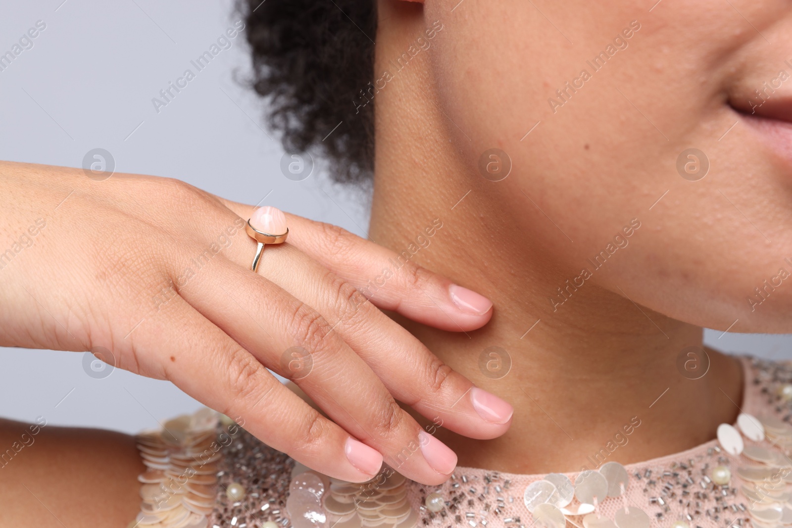 Photo of Young woman wearing elegant ring on light grey background, closeup