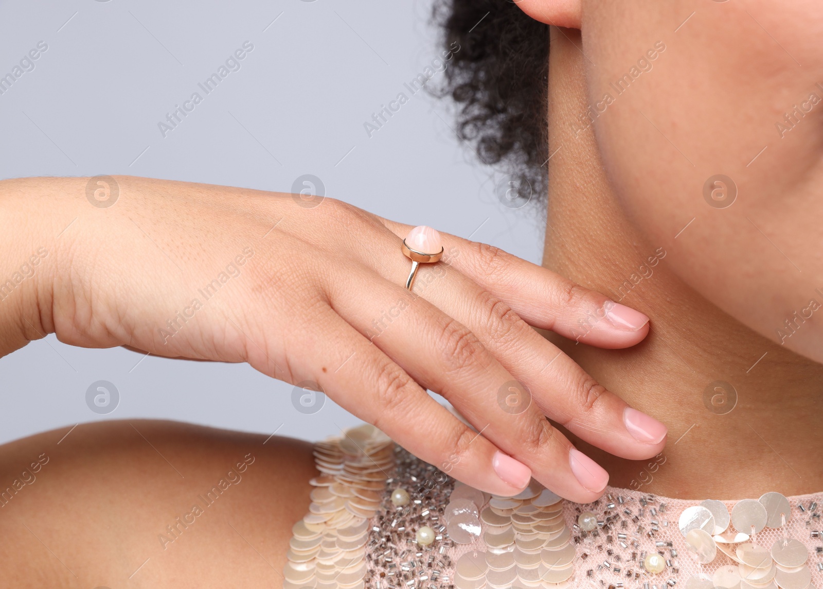 Photo of Young woman wearing elegant ring on light grey background, closeup