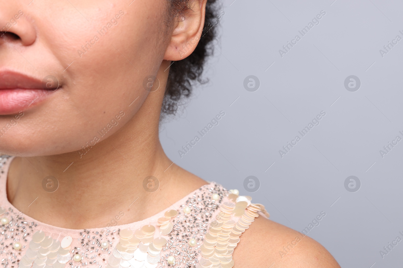 Young woman with pierced ear on light grey background, closeup. Space for text Photo of Young woman with pierced ear on light grey background, closeup. Space for text