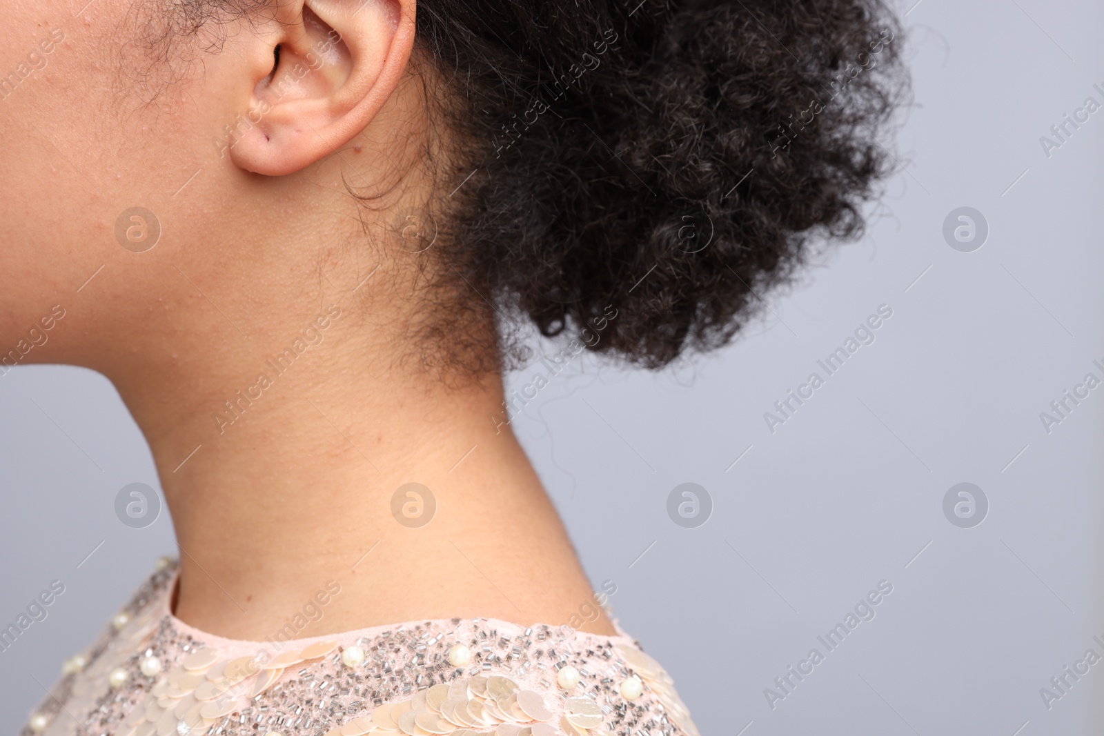 Young woman with pierced ear on light grey background, closeup. Space for text Photo of Young woman with pierced ear on light grey background, closeup. Space for text