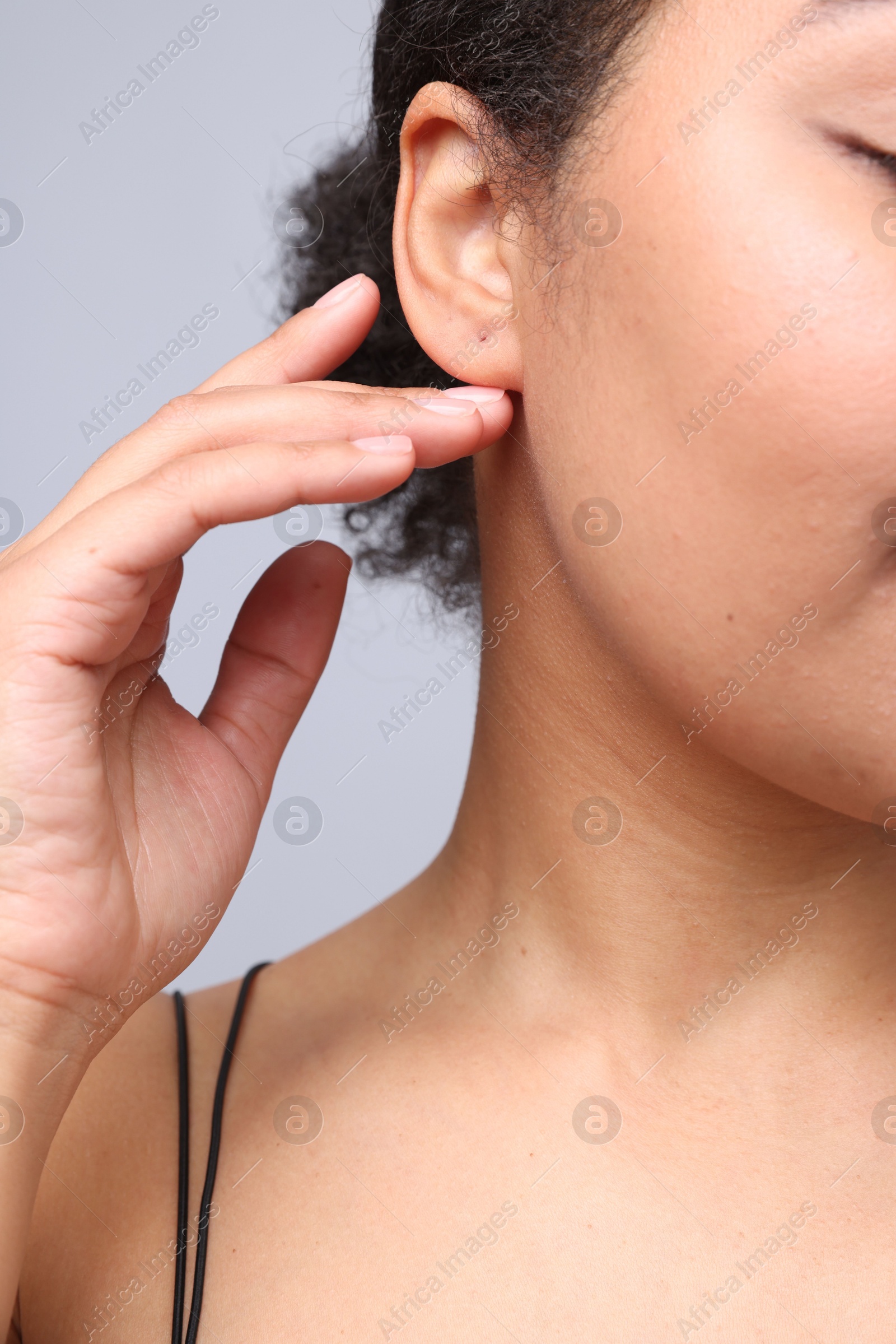Young woman with pierced ear on light grey background, closeup Photo of Young woman with pierced ear on light grey background, closeup