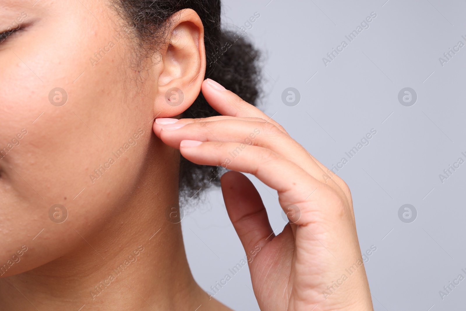 Young woman with pierced ear on light grey background, closeup Photo of Young woman with pierced ear on light grey background, closeup