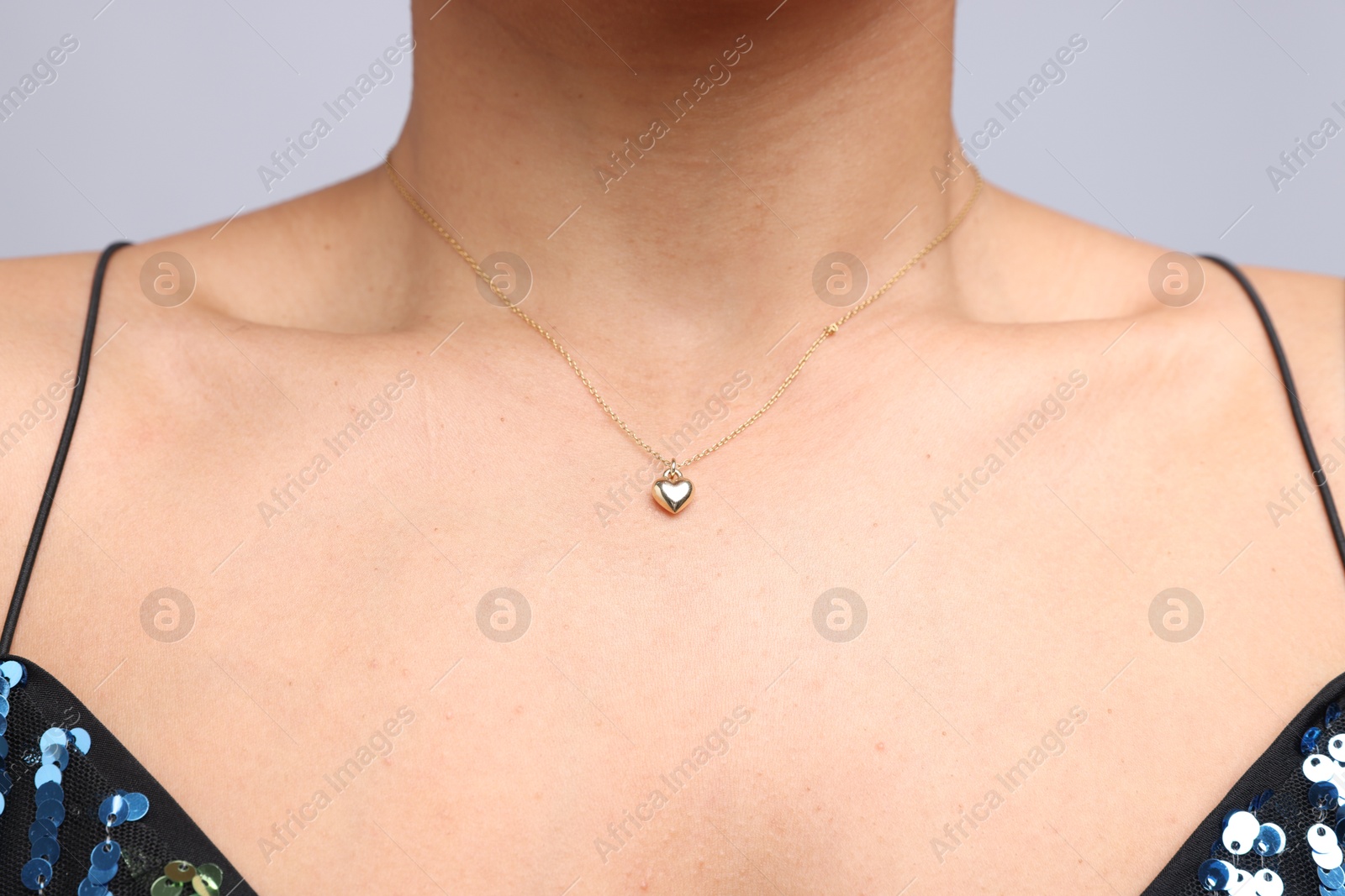 Photo of Young woman wearing elegant gold necklace on light grey background, closeup