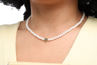 Photo of Young woman wearing elegant pearl necklace on white background, closeup