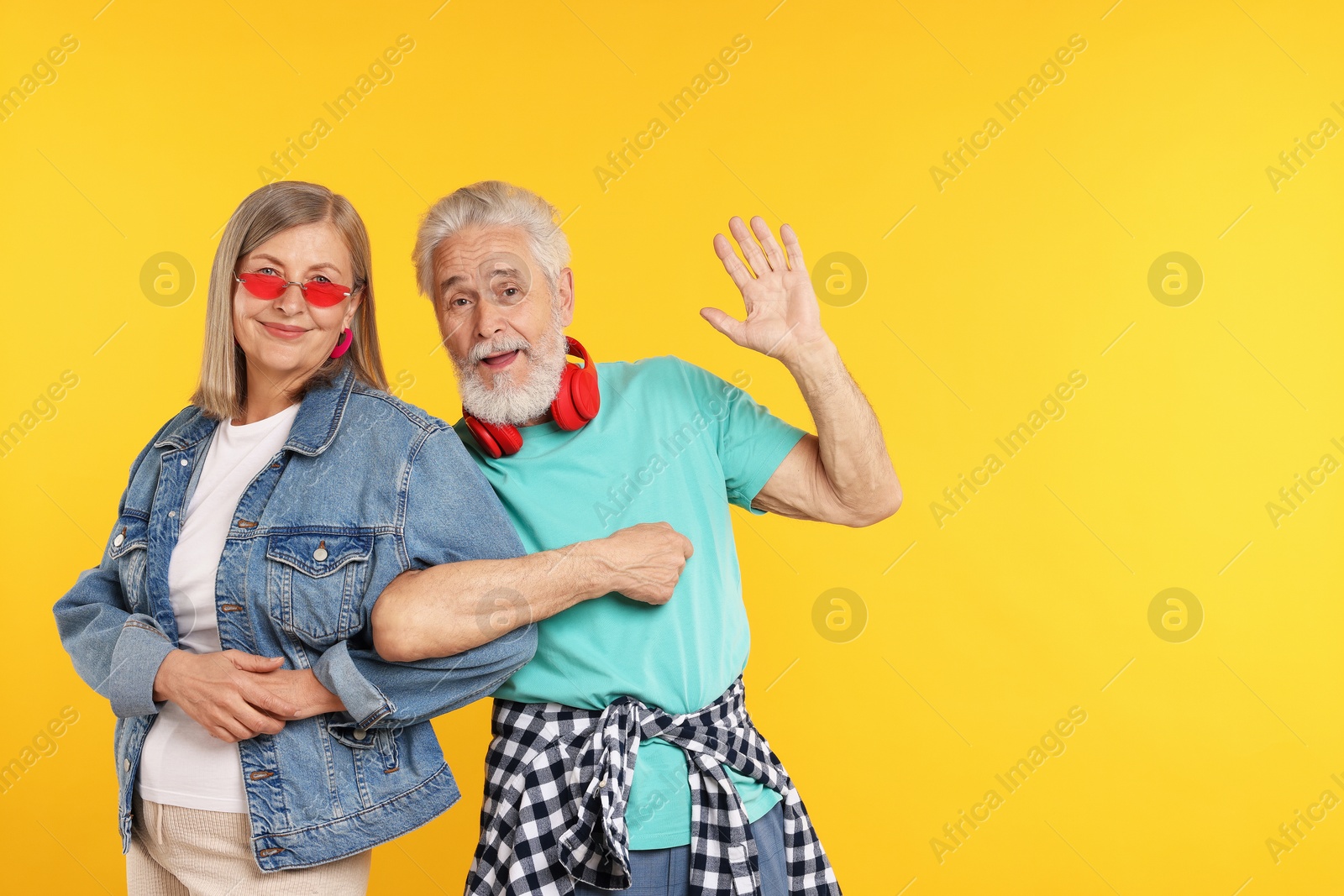 Senior couple in stylish outfits on orange background, space for text Photo of Senior couple in stylish outfits on orange background, space for text