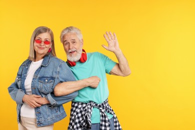 Photo of Senior couple in stylish outfits on orange background, space for text