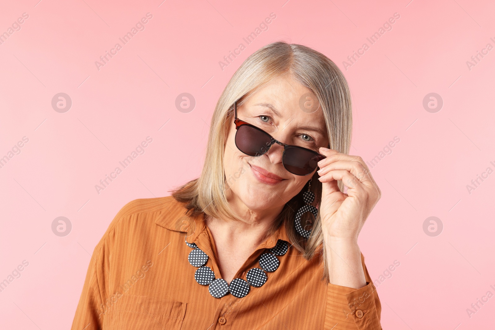 Senior woman in stylish outfit on pink background Photo of Senior woman in stylish outfit on pink background