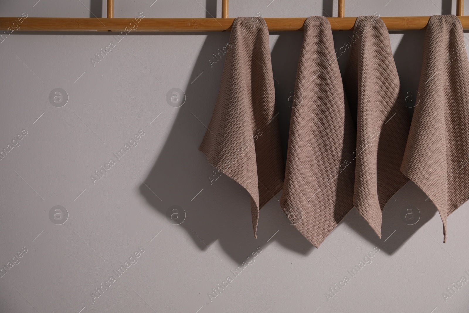 Clean waffle towels hanging on light wall, space for text Photo of Clean waffle towels hanging on light wall, space for text