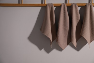 Photo of Clean waffle towels hanging on light wall, space for text