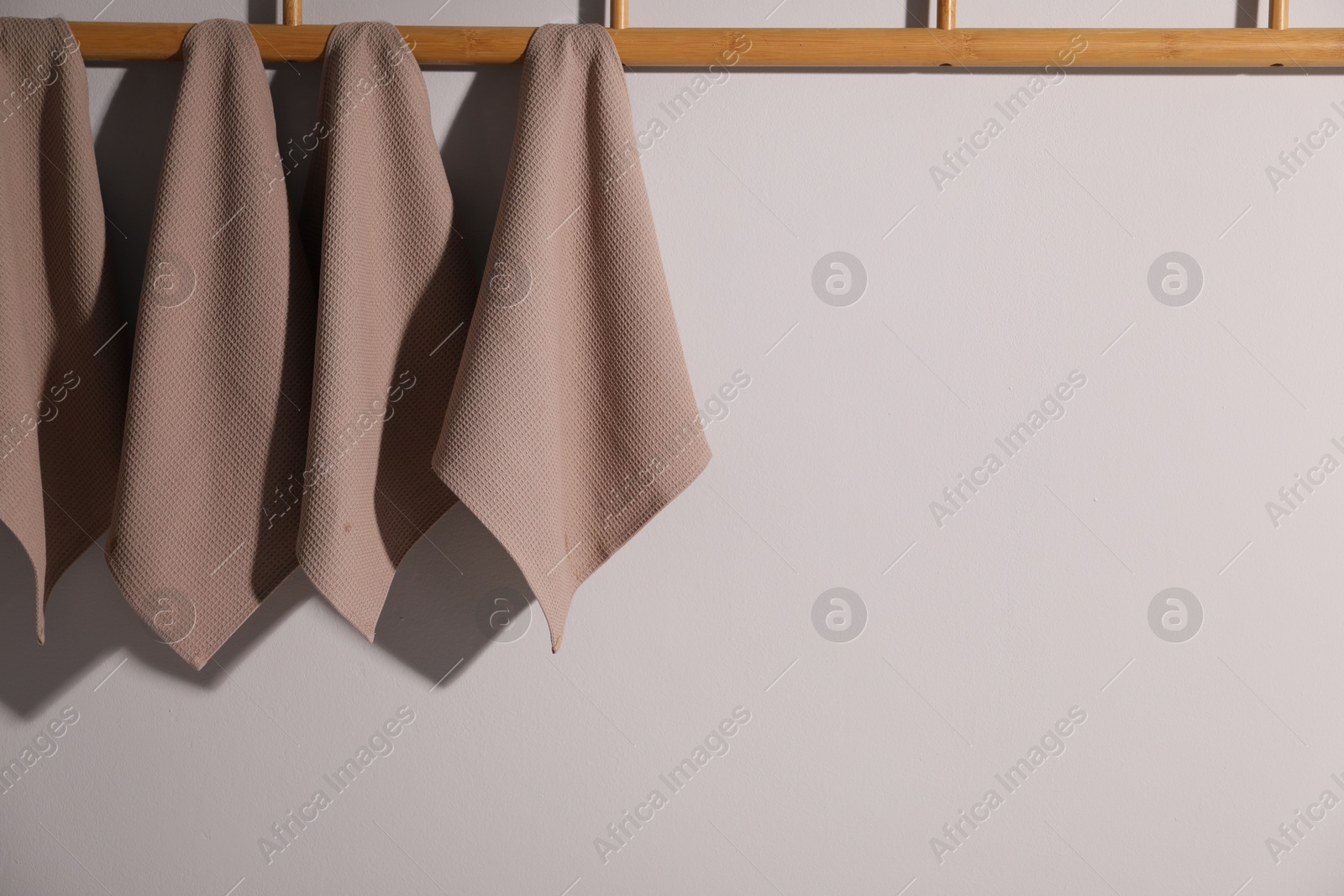 Clean waffle towels hanging on light wall, space for text Photo of Clean waffle towels hanging on light wall, space for text