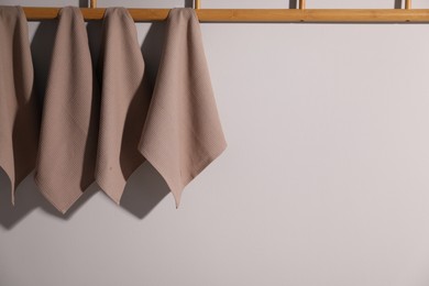 Photo of Clean waffle towels hanging on light wall, space for text