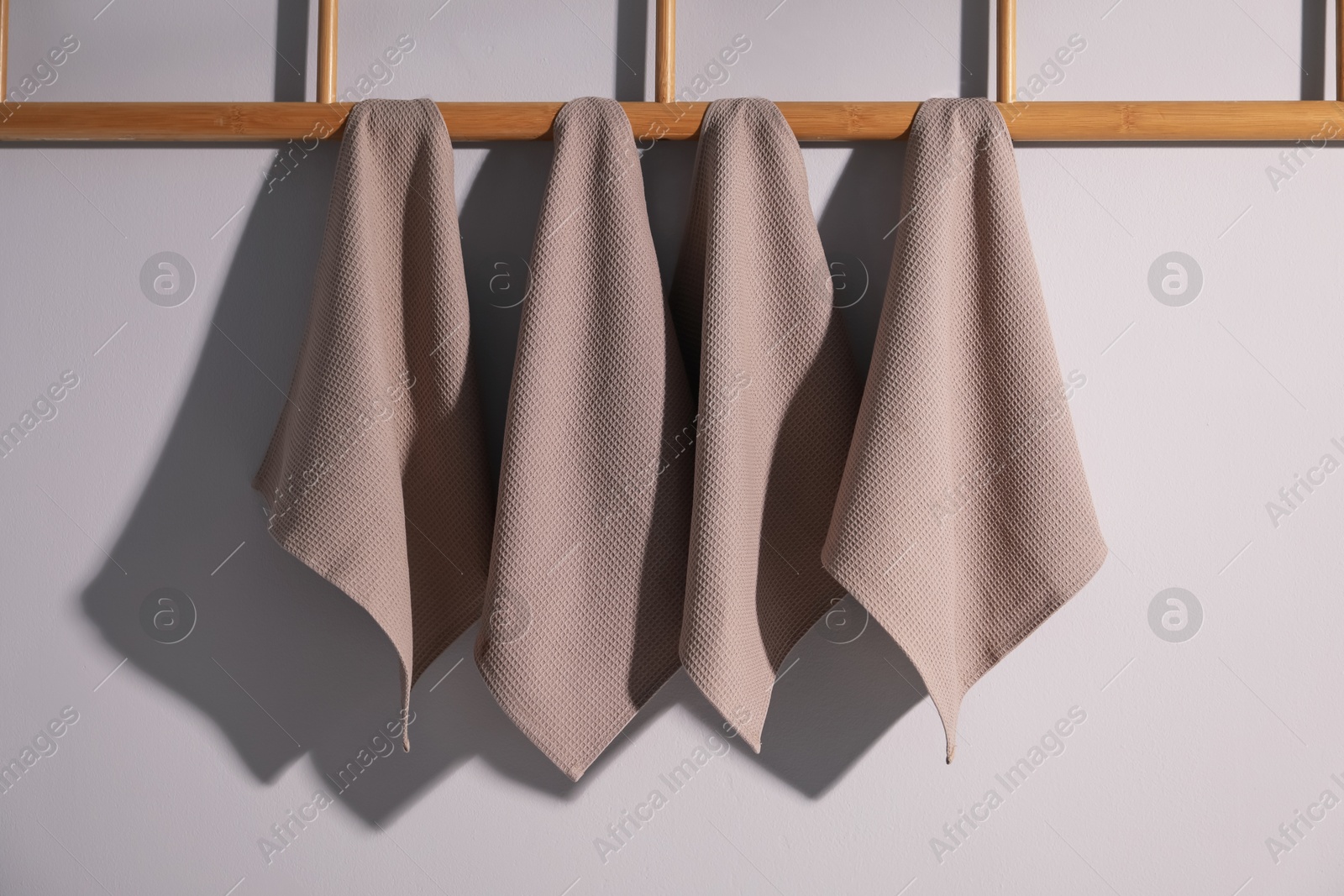 Clean waffle towels hanging on light wall Photo of Clean waffle towels hanging on light wall