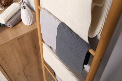 Photo of Clean waffle towels on wooden rack in bathroom, above view