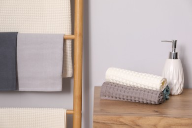 Photo of Clean waffle towels and hand soap on wooden dresser