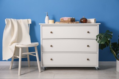 Photo of Clean waffle towel on chair and dresser near blue wall