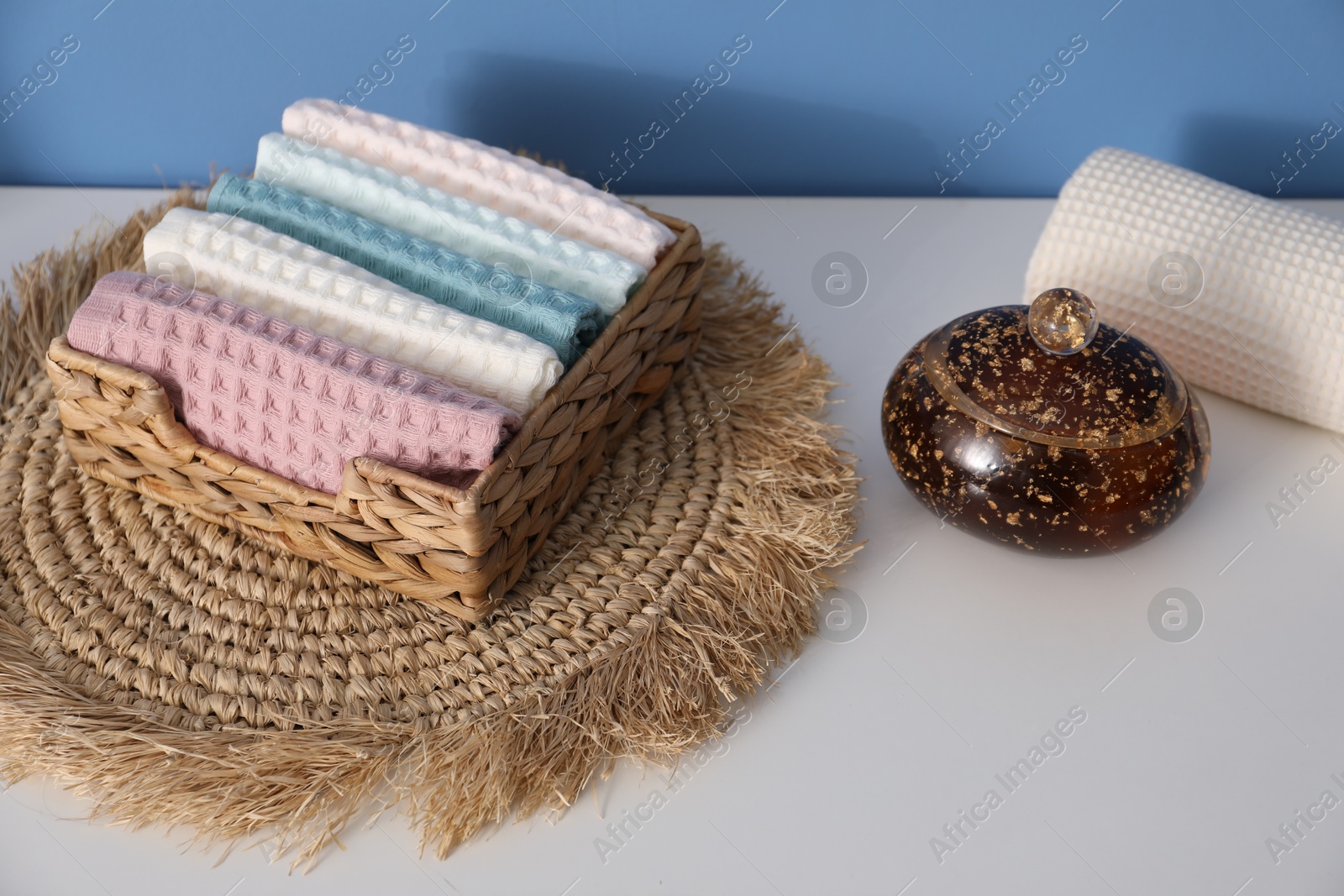 Clean waffle towels in wicker basket on white dresser in bathroom, closeup Photo of Clean waffle towels in wicker basket on white dresser in bathroom, closeup