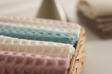Photo of Clean waffle towels in wicker basket on white table in bathroom, closeup