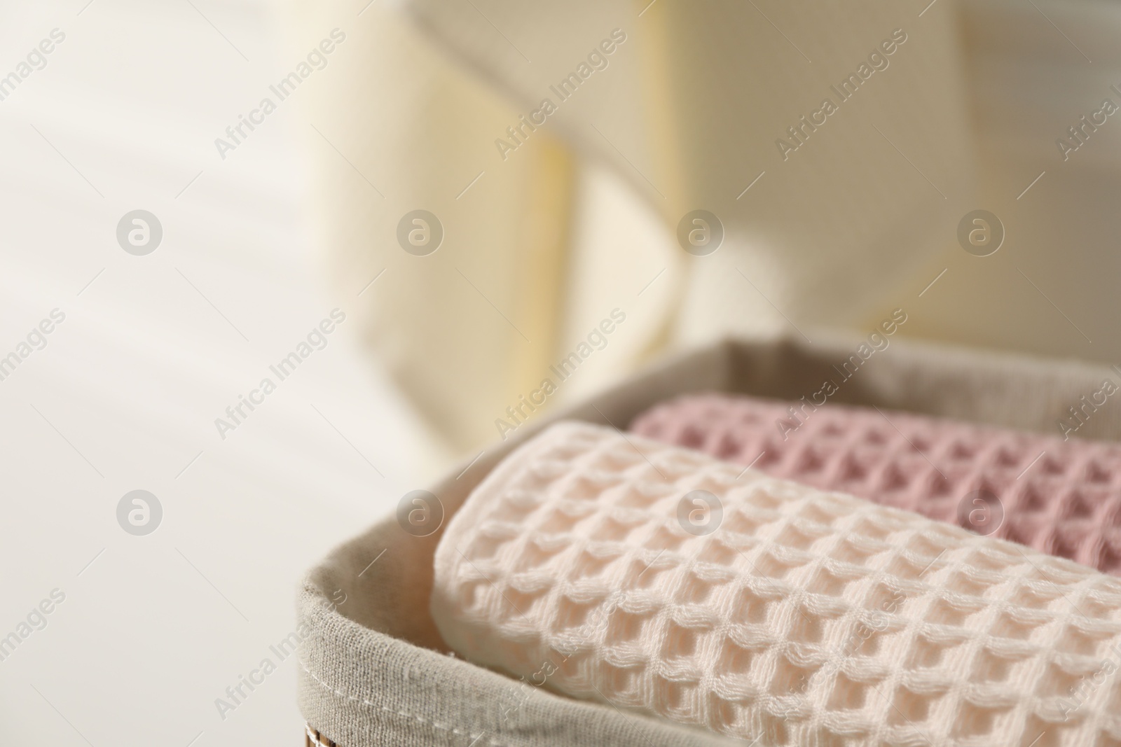 Clean waffle towels in basket on blurred background, closeup. Space for text Photo of Clean waffle towels in basket on blurred background, closeup. Space for text