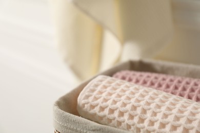 Photo of Clean waffle towels in basket on blurred background, closeup. Space for text