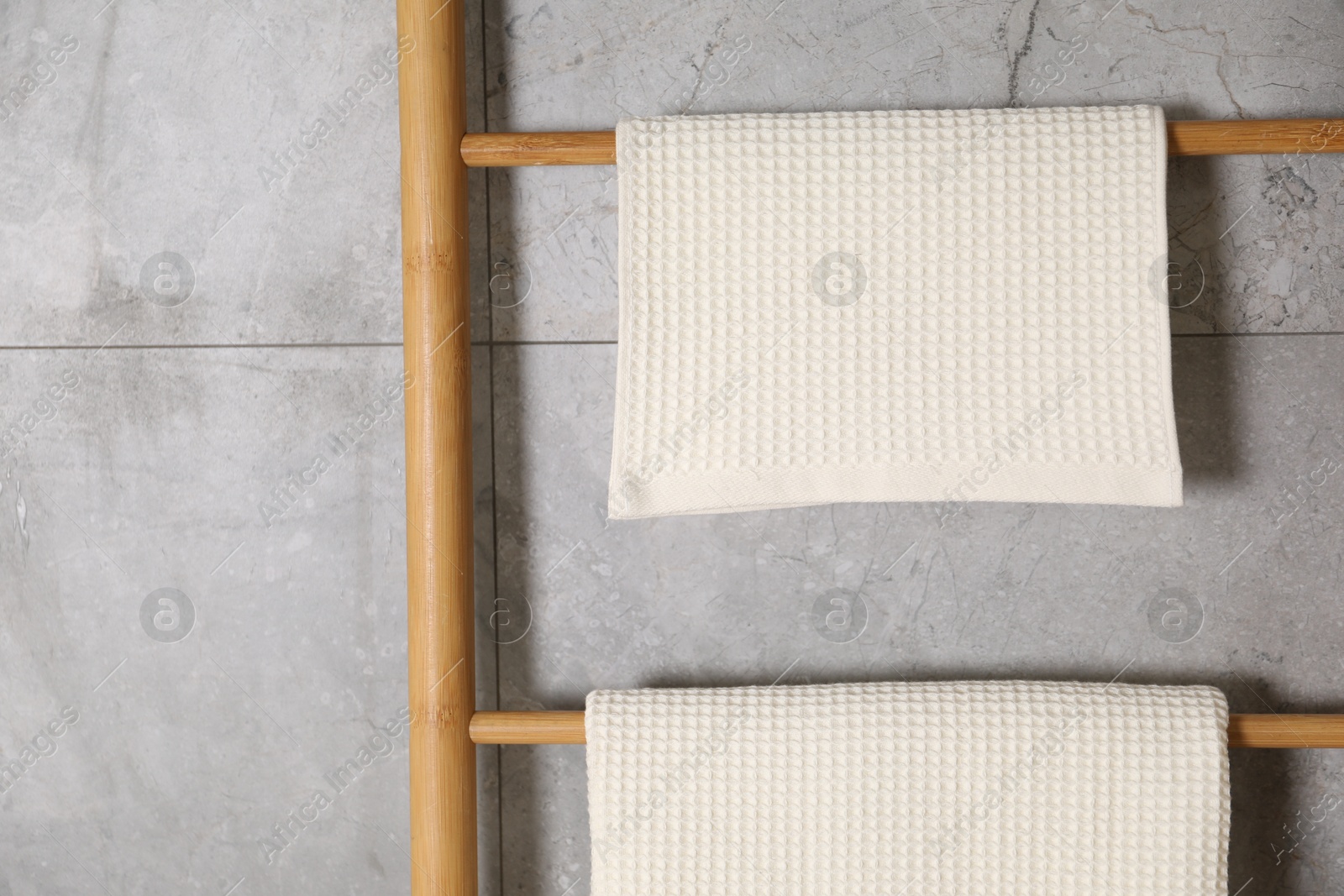 Clean waffle towels on wooden rack near grey wall, closeup Photo of Clean waffle towels on wooden rack near grey wall, closeup