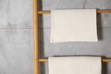 Photo of Clean waffle towels on wooden rack near grey wall, closeup