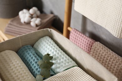 Photo of Clean waffle towels and branch in basket indoors, closeup