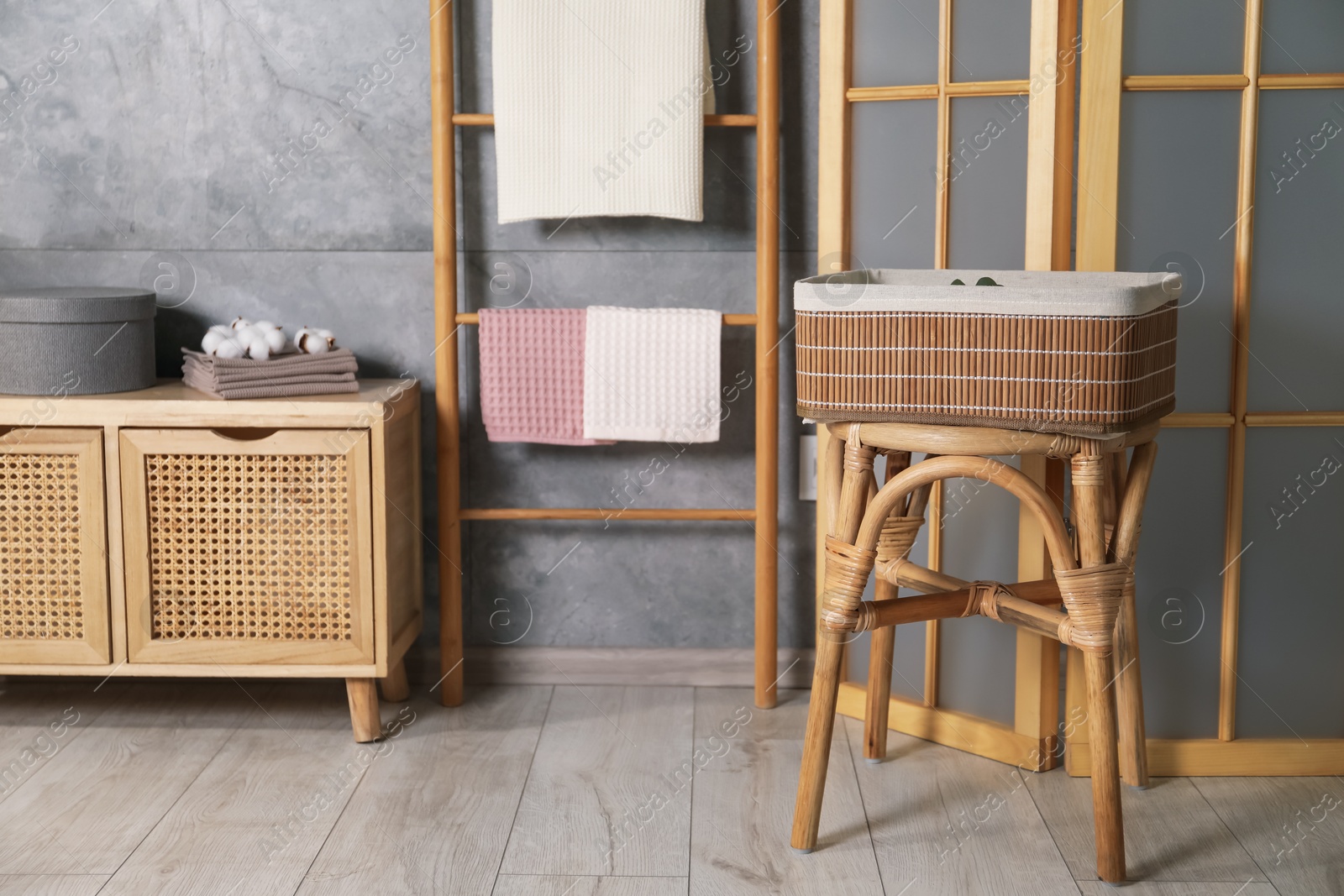 Clean waffle towels, wooden rack and dresser near grey wall in bathroom Photo of Clean waffle towels, wooden rack and dresser near grey wall in bathroom