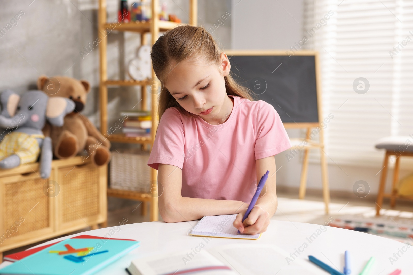 Photo of Dyslexia. Little girl writing at table indoors