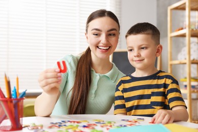 Photo of Dyslexia. Mother and her son learning letters at table indoors