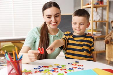Photo of Dyslexia. Mother and her son learning letters at table indoors