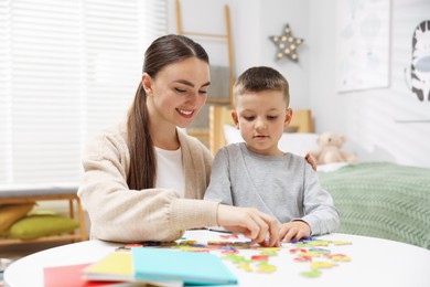 Photo of Dyslexia. Mother and her son learning letters at table indoors