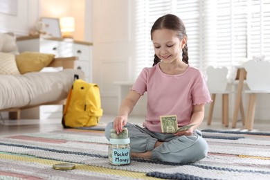 Photo of Girl putting her pocket money into jar at home. Space for text