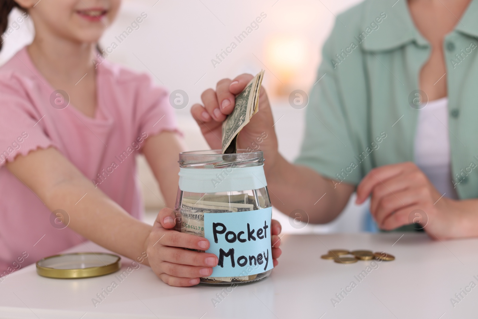 Mother giving her daughter pocket money at table indoors, closeup Photo of Mother giving her daughter pocket money at table indoors, closeup