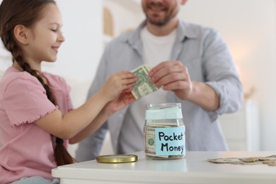 Photo of Father giving his daughter pocket money at table indoors, closeup