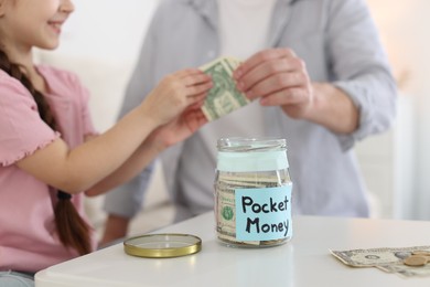 Photo of Father giving his daughter pocket money at table indoors, closeup