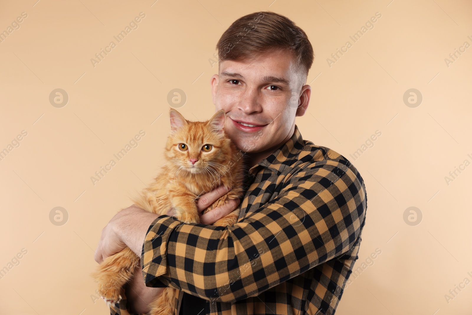 Photo of Man with cute ginger cat on beige background