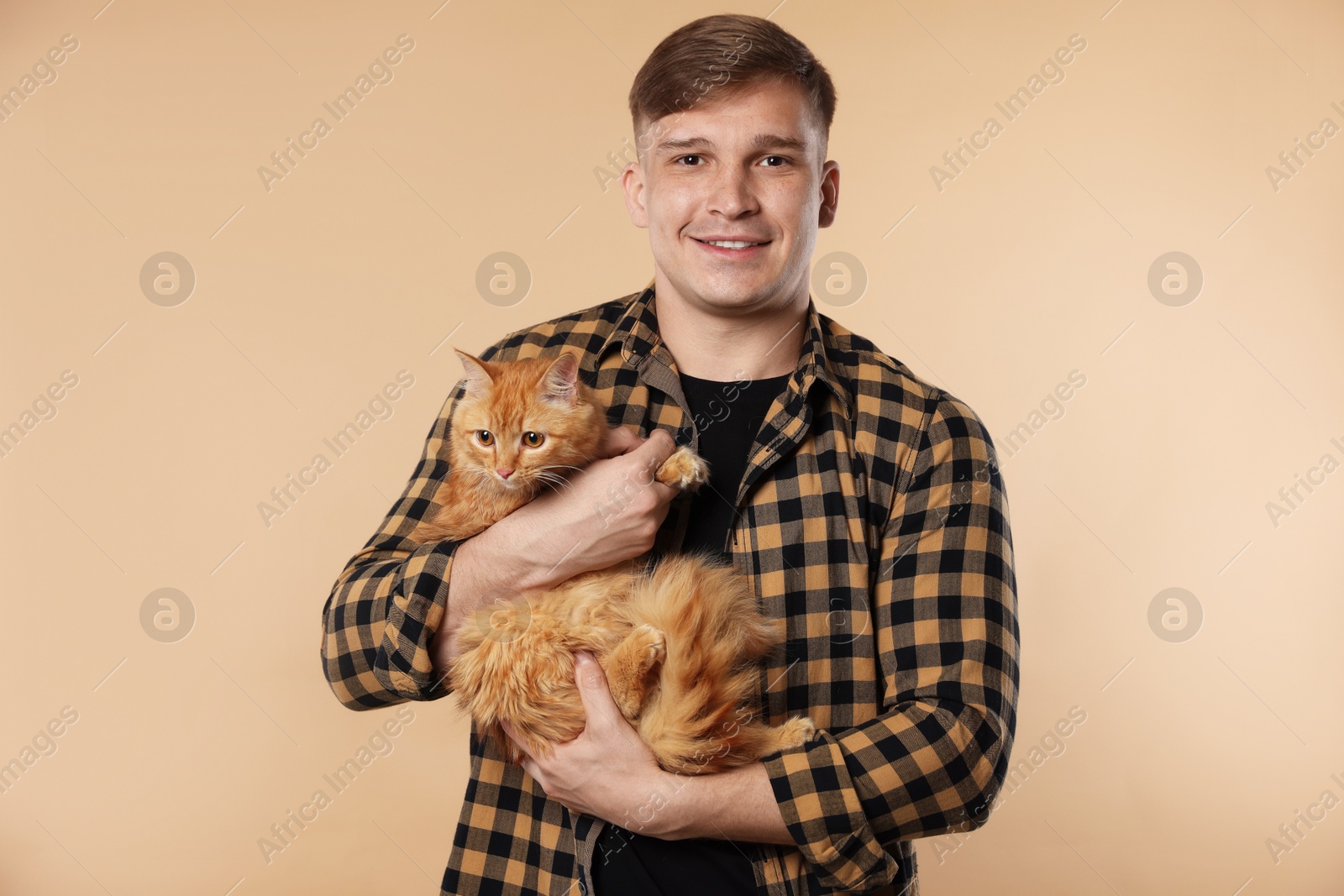 Photo of Man with cute ginger cat on beige background