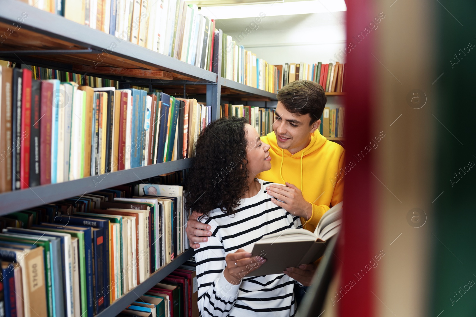 Photo of Students studying together near shelves with books in public library