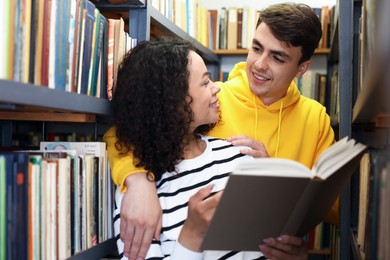 Photo of Students studying together near shelves with books in public library