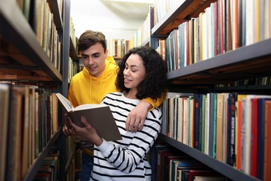 Photo of Students studying together near shelves with books in public library