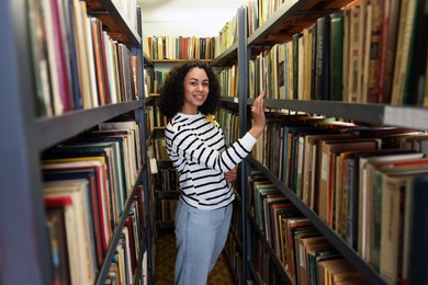 Photo of Woman with laptop near shelves in public library