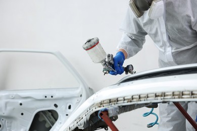 Photo of Worker painting car in body shop, closeup