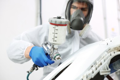 Photo of Worker painting car in body shop, selective focus