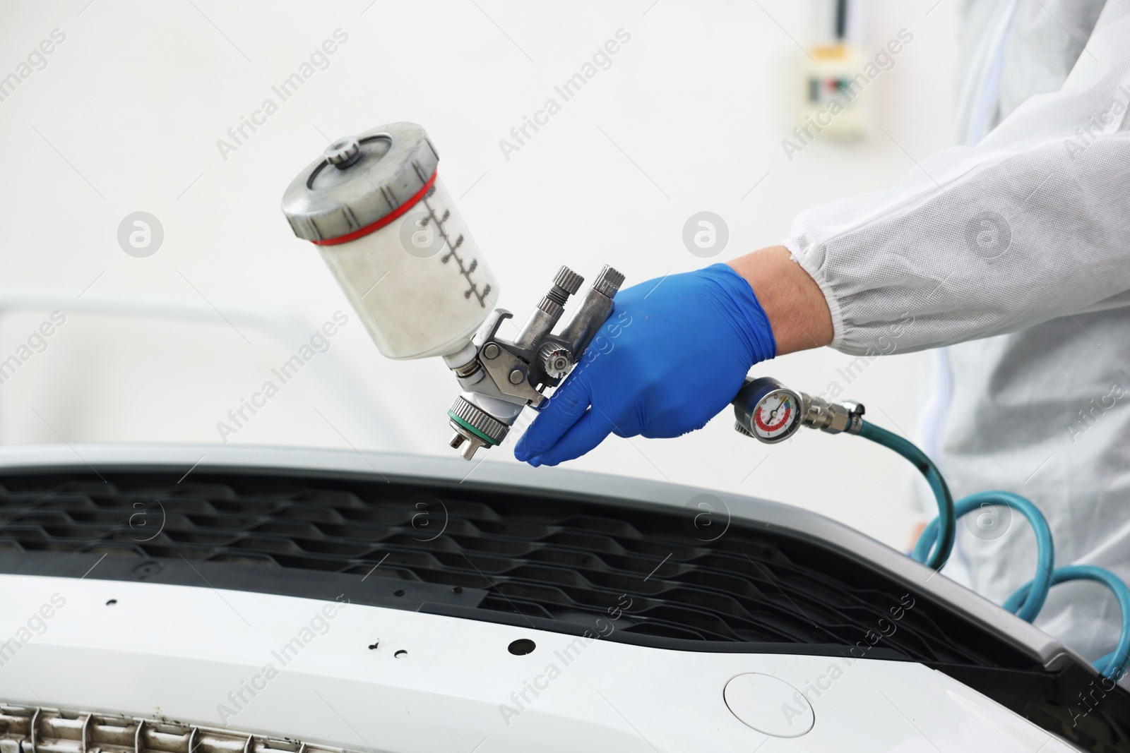 Worker painting car in body shop, closeup Photo of Worker painting car in body shop, closeup