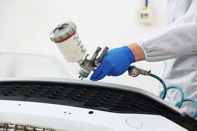 Photo of Worker painting car in body shop, closeup